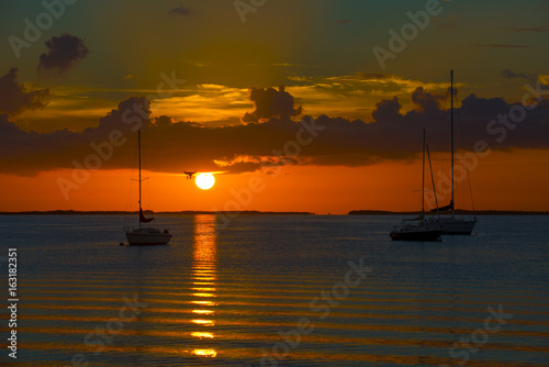 sunset over ocean bay with anchored boats © kevin