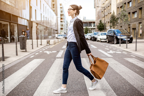 Canvas-taulu Young businesswoman crossing the street at the modern office district in Lyon ci