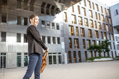 Lifestyle portrait of a young businesswoman swinging bag outdoors at the modern residential district © rh2010