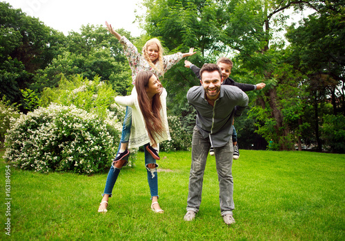 Happy joyful family in park fun playing imitation flight