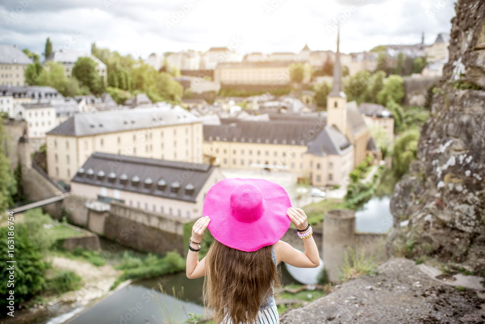 Fototapeta premium Female traveler standing back with pink hat and enjoy beautiful cityscape view on the old town in Luxembourg city