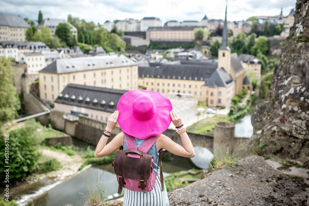 Fototapeta premium Female traveler standing back with pink hat and enjoy beautiful cityscape view on the old town in Luxembourg city