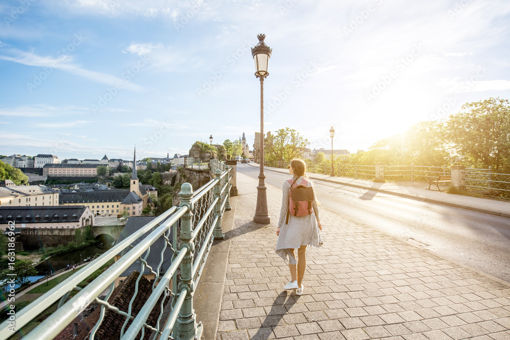 Woman walking on the bridge with great view on the old town of Luxembourg city - obrazy, fototapety, plakaty 