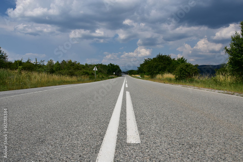 Empty asphalt country road with white lines in a sunny summer day, Bulgarian countryside