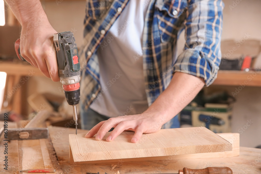 Carpenter driving screw nail into timber in workshop Carpenter driving screw nail into timber in workshop