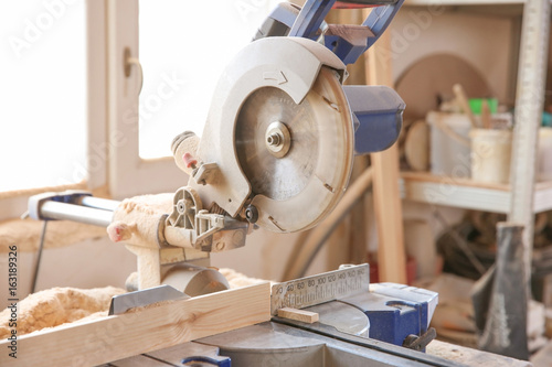 Circular saw and timber strip on table near window in carpenter's workshop