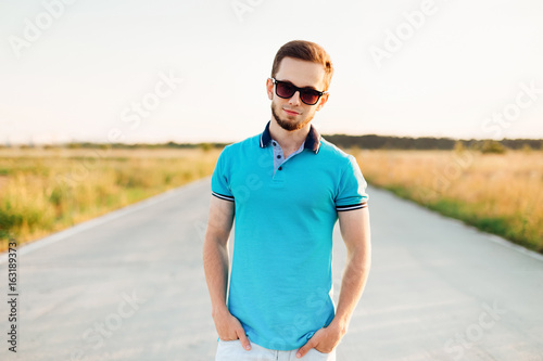Stylish man in blue polo holding his hand in his pockets on an e