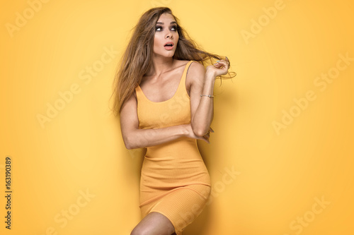 Female model posing on yellow.