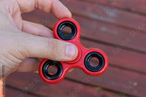red fidget spinner in hand on wooden background