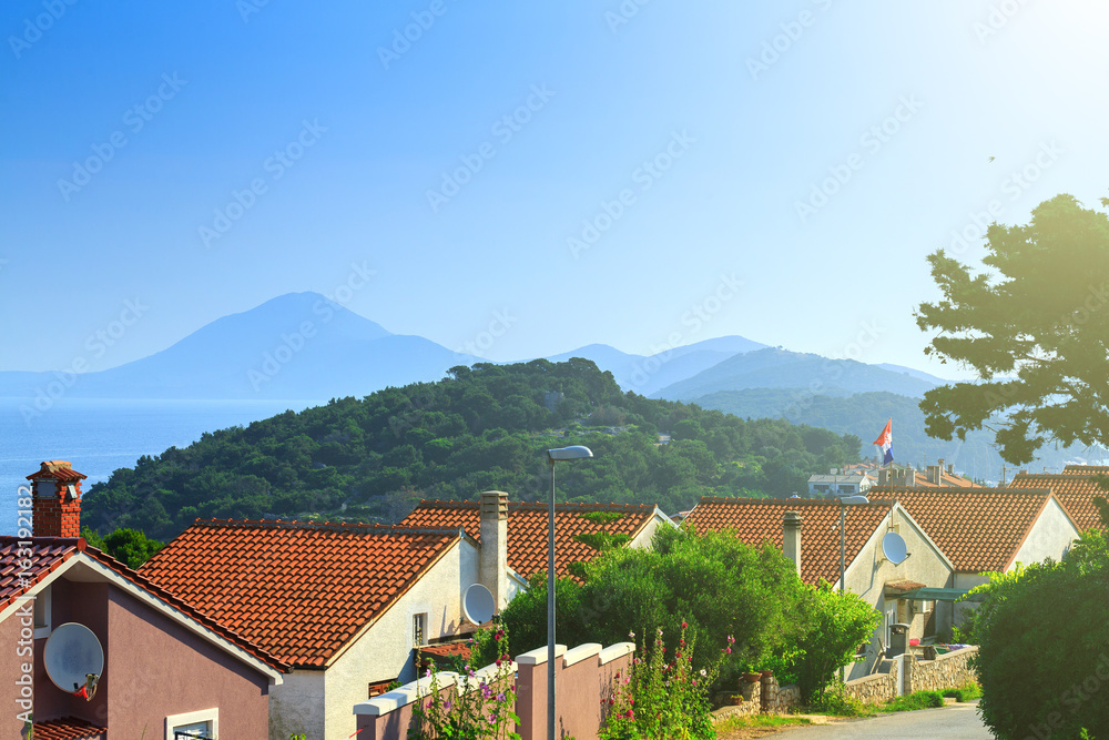 Traditional european Mediterranean architectural style, streets & houses with terracotta roofs, surrounded by cypress, palm, olive, pine trees, on coast azure sea. Location of the prestigious estates