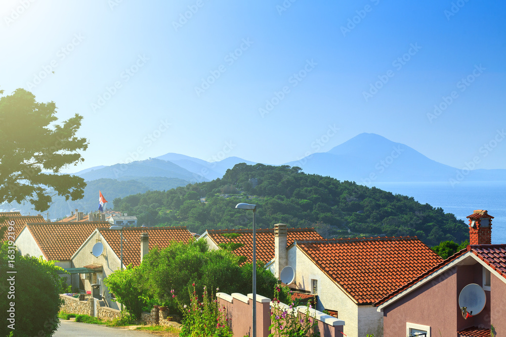 Traditional european Mediterranean architectural style, streets & houses with terracotta roofs, surrounded by cypress, palm, olive, pine trees, on coast azure sea. Location of the prestigious estates