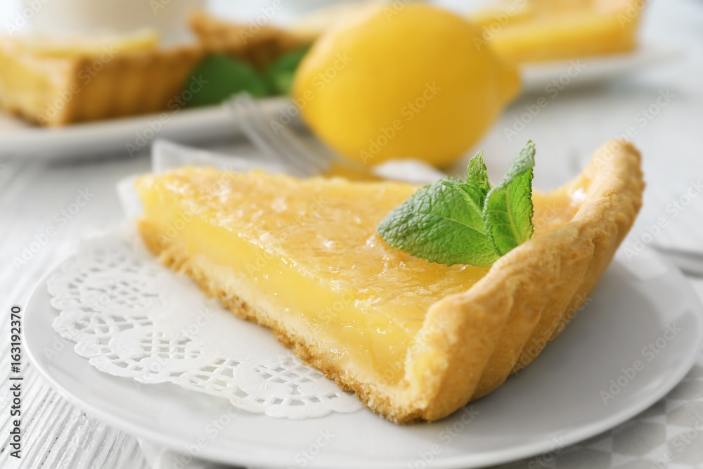 Piece of lemon tart with mint on plate