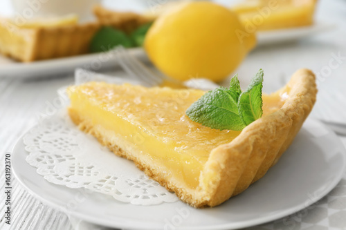 Piece of lemon tart with mint on plate