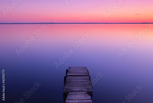 Landscape on the lake after sunset with a wooden pier on a long exposure
