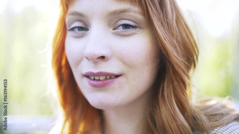 Close up of a young and pretty redhead drinking tea or coffee from a large brown mug in a park. Handheld real time close up shot Close up of a young and pretty redhead drinking tea or coffee from a large brown mug in a park. Handheld real time close up shot