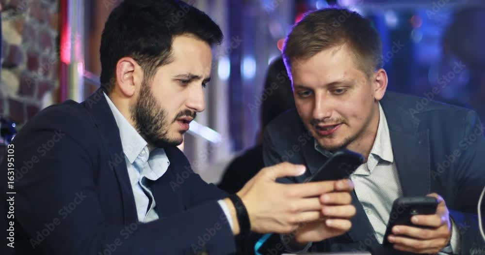 Two young attractive men have a business conversation in cafe entertainment Two young attractive men have a business conversation in cafe entertainment