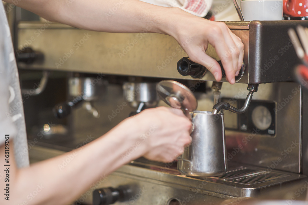 Young man bartender frothing milk foam on a barista machine Young man bartender frothing milk foam on a barista machine