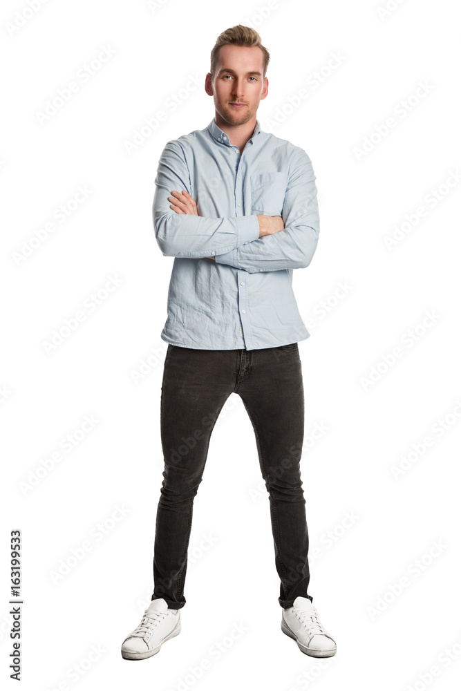 Fototapeta premium Good looking blonde man wearing a light blue shirt standing against a white background looking at camera.