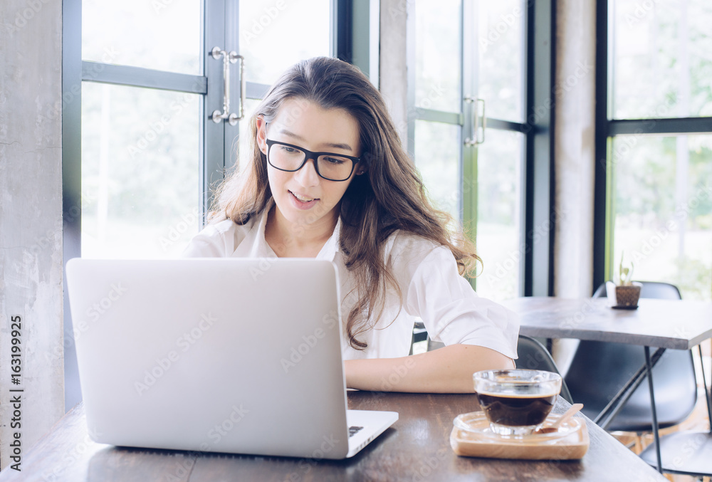 Portrait of young mixed race businesswoman (Her dad is British, Her mom is Thailand) take a coffee break and looking somethings on her laptop. Portrait of young mixed race businesswoman (Her dad is British, Her mom is Thailand) take a coffee break and looking somethings on her laptop.