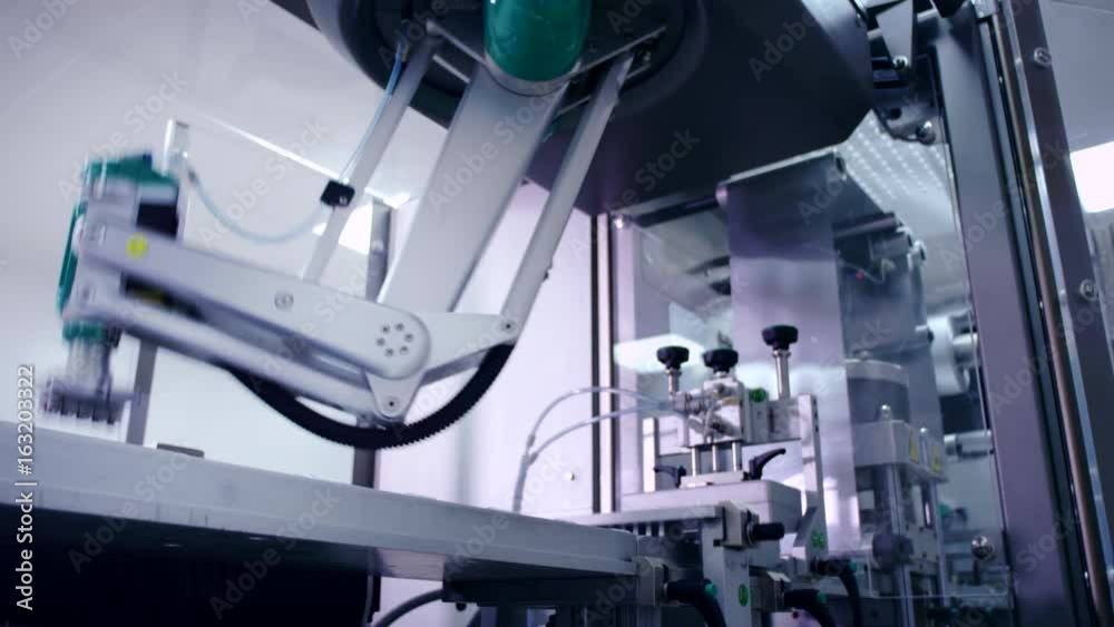 Robotic arm working at automated production line. Modern technology. Industrial equipment at pharmaceutical plant. Packaging machine. Pharmaceutical manufacturing equipment. Medicine manufacturing