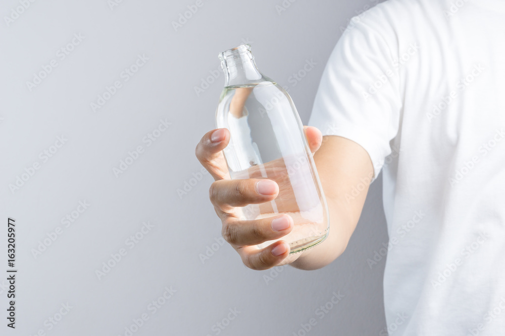 Hand holding glass water bottle Hand holding glass water bottle