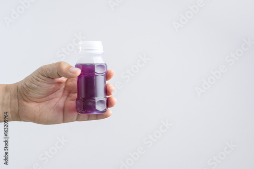 Hand holding a plastic bottle of purple herbal drink from Butterfly pea with lemonade