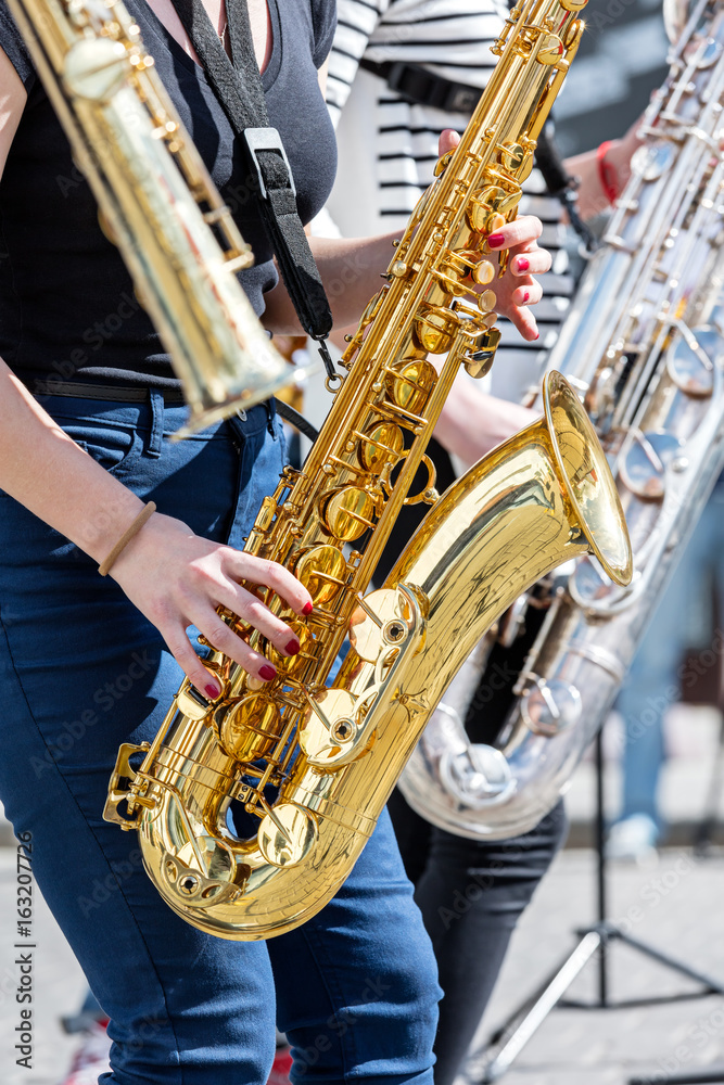 Naklejka premium quartet of young musicians playing saxophones during street performance