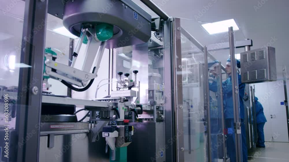 Engineer starting packaging line at pharmaceutical plant. Pharmaceutical manufacturing line. Factory worker at industrial workshop. Packaging machine at medical factory. Pharmaceutical industry