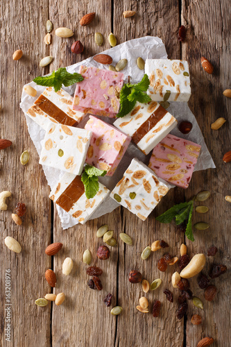 Sweet nougat with nuts, decorated with mint closeup on the table. vertical top view photo