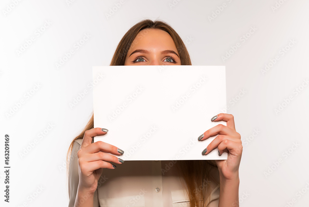 The girl is holding a sheet of blank paper in front of her The girl is holding a sheet of blank paper in front of her