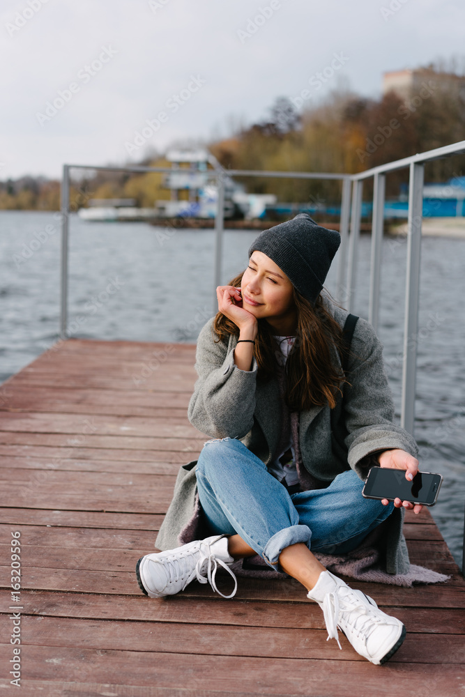 Young pretty girl on wooden bench on old pier