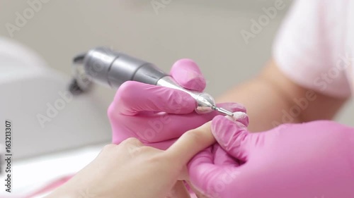 Hardware manicure. Removal of old gel varnish in the salon. Manicure master doing beauty procedure for client, closeup footage photo