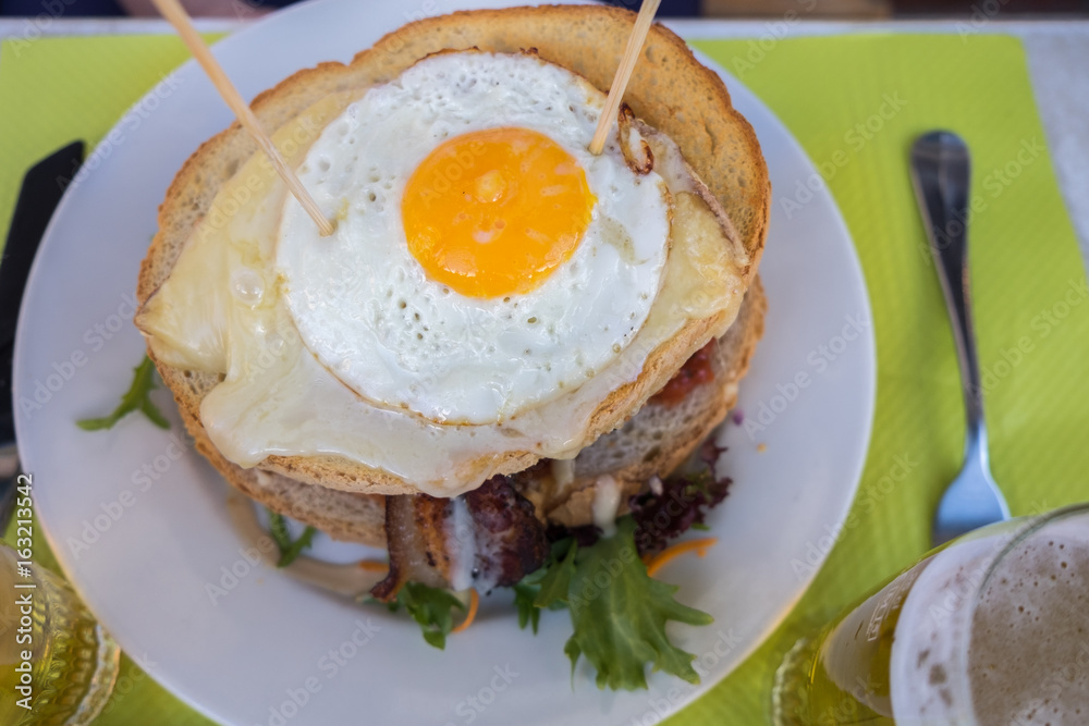 Beer and famous hamburger with fried eggs, beef and bacon at an cafe in Annecy. France Beer and famous hamburger with fried eggs, beef and bacon at an cafe in Annecy. France