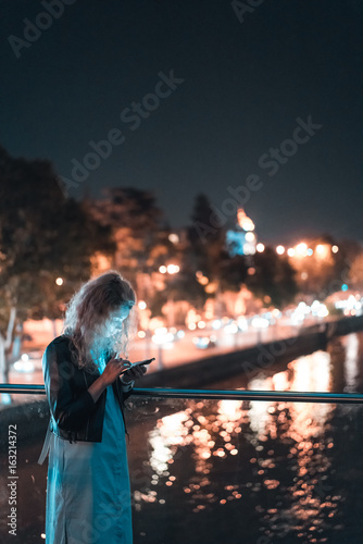 Girl with a smartphone on a bridge
