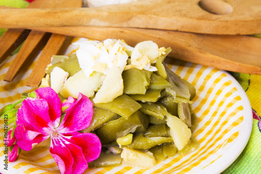 Bowl of green beans with egg on tablecloth with flowers Bowl of green beans with egg on tablecloth with flowers