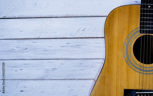 Acoustic guitar resting against a yellow background with copy space