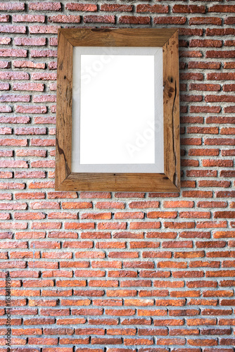 Empty wooden picture frame hanging on a brick wall.