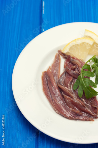 anchovies with lemon on white plate