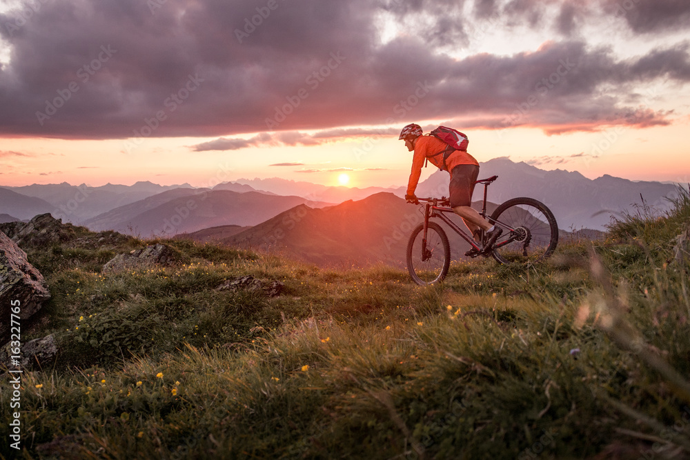 Male mountainbiker at sunset in the mountains - obrazy, fototapety, plakaty 