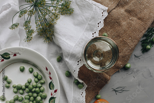 Close-up above view of the glass placed on the rustic tissue near the dry herb and plate with peas. photo