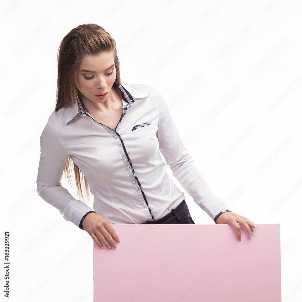 Young curious woman portrait of a confident businesswoman showing presentation, pointing placard gray background. Ideal for banners, registration forms, presentation, landings, presenting concept..