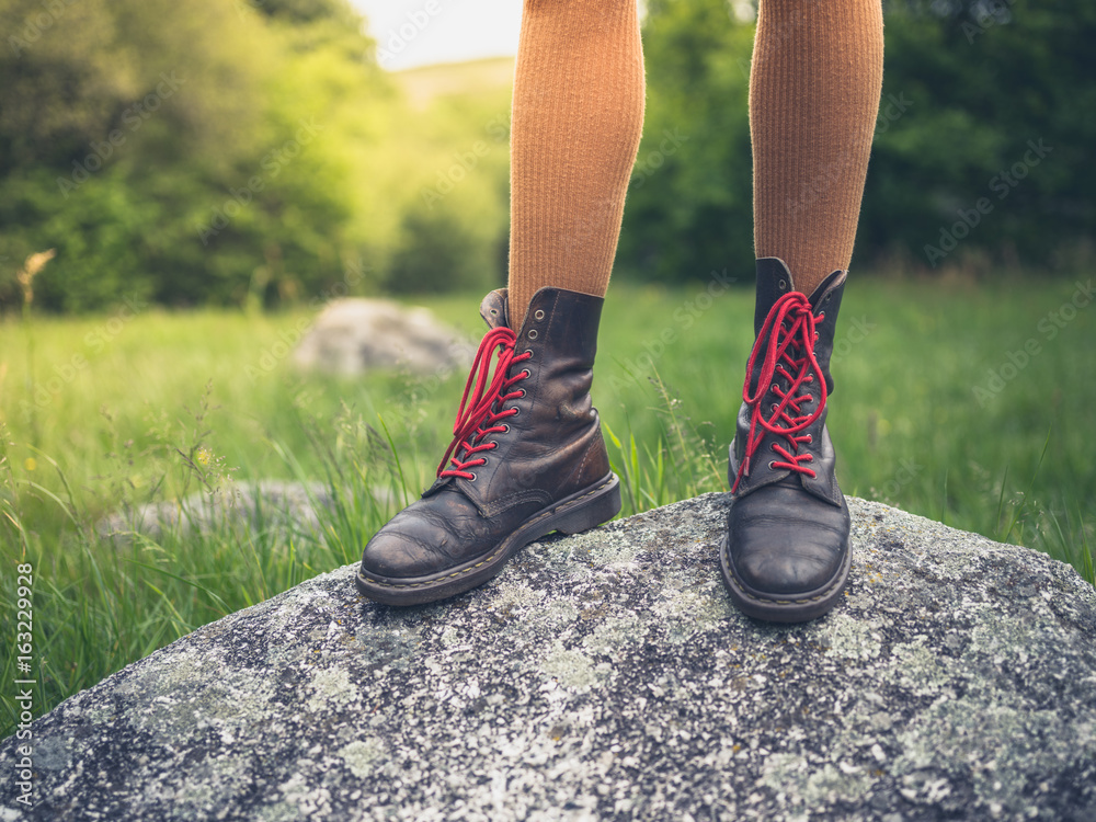 Young woman in boots standing on rock Young woman in boots standing on rock