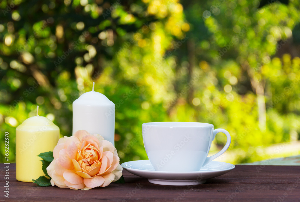 A cup of hot tea in the garden, fragrant roses and candles. Romantic concept. Copy space