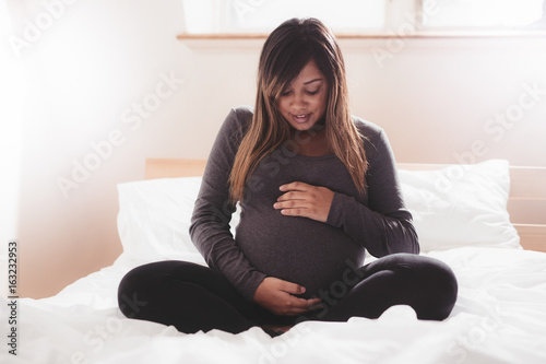 Wallpaper Mural Beautiful pregnant woman sitting on bed at home