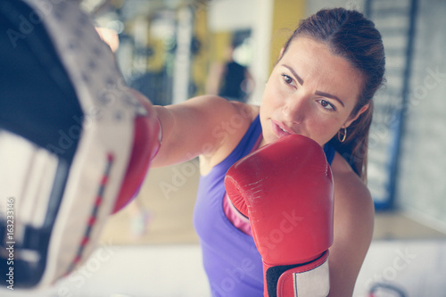  Woman boxer hitting the glove of his sparring partner. Woman workout in gym. © liderina
