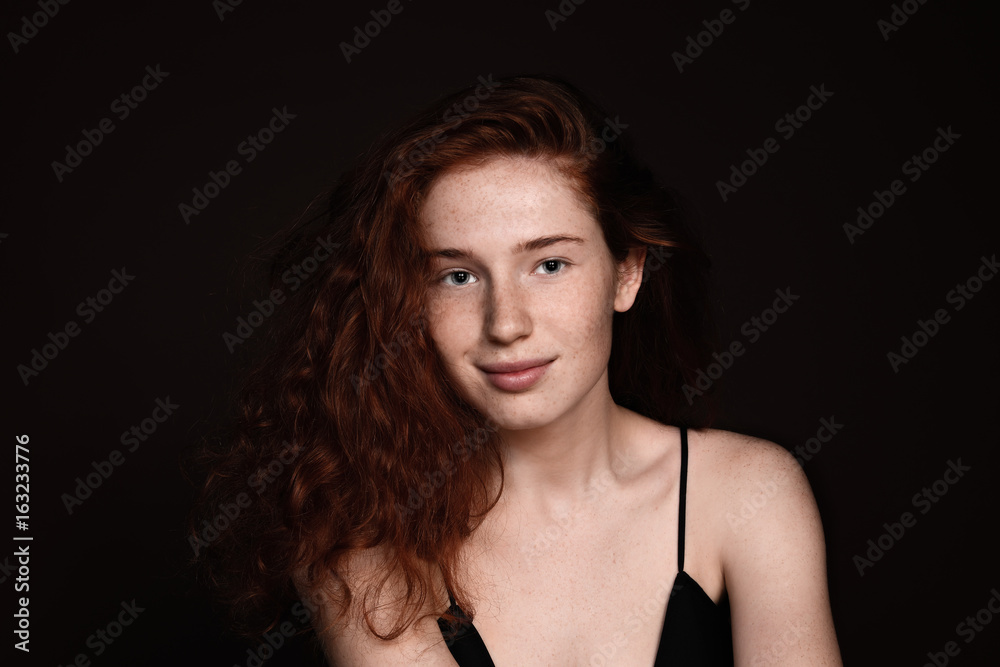 beautiful redhead woman with perfect clean skin smiling at camera, isolated on black