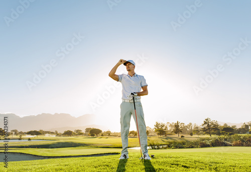 Male golfer holding golf club on field