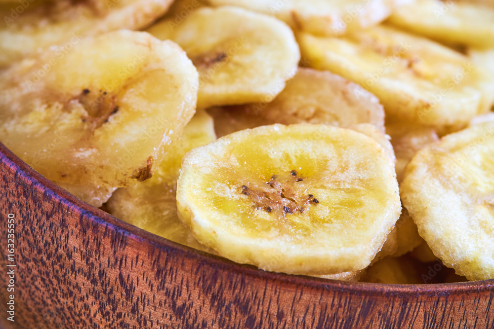 Homemade banana chips (dried and fried banana slices) in wooden bowl
