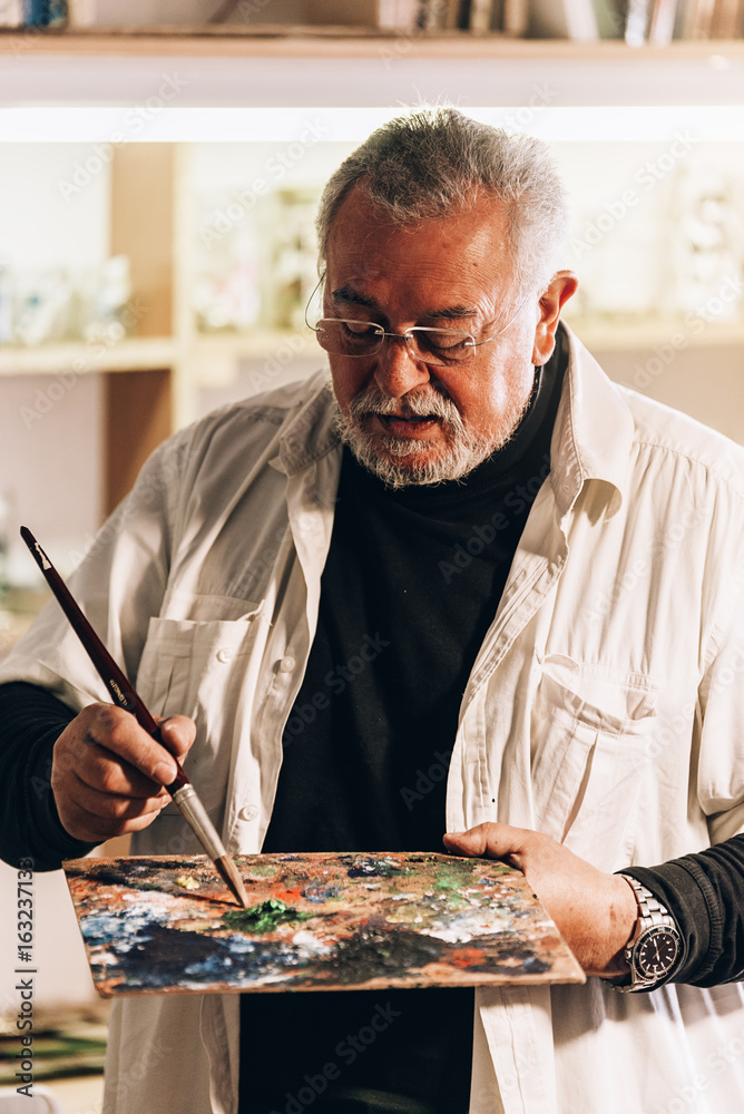 Old man artist painting oils in his studio. Old man artist painting oils in his studio.