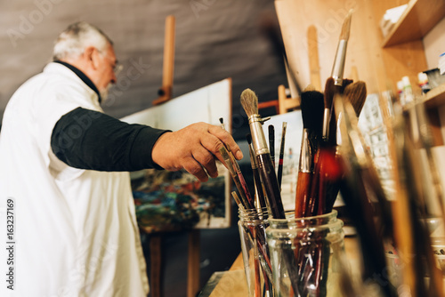 Foto Old man artist painting oils in his studio.